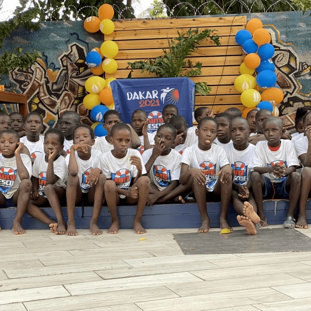 Groupe d'enfants en t-shirts Auto-Rescue® devant la banderole Dakar 2021