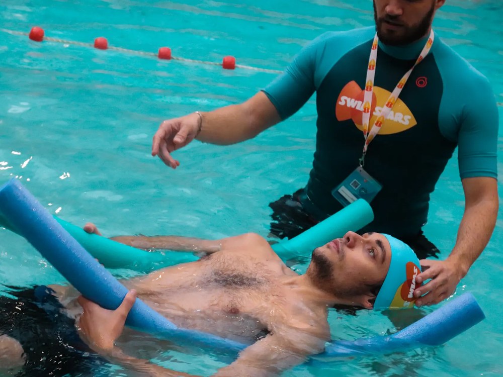 Un adulte en cours de natation avec son coach