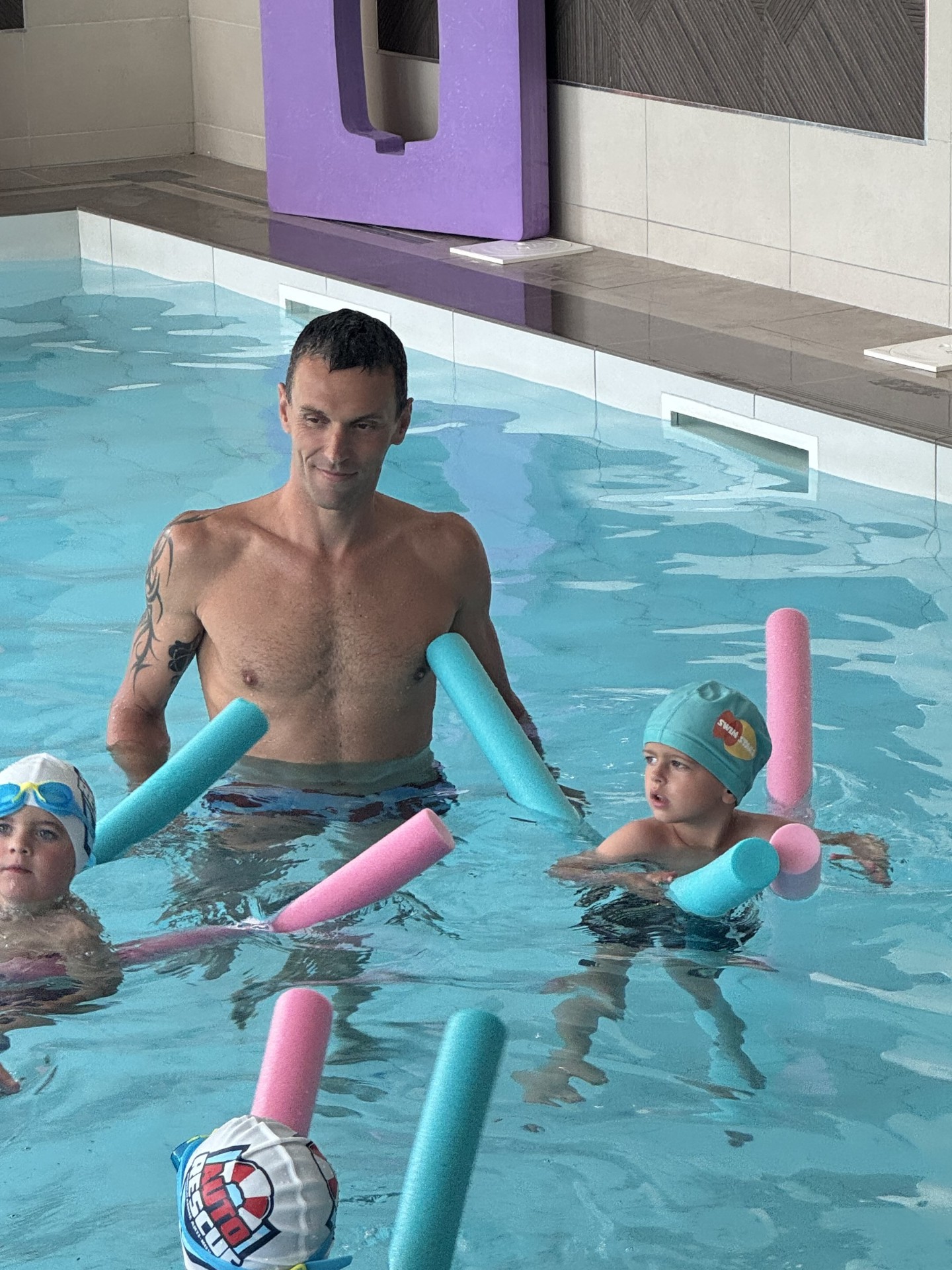 Alexis Hanquinquant souriant dans la piscine avec des enfants Swim Stars