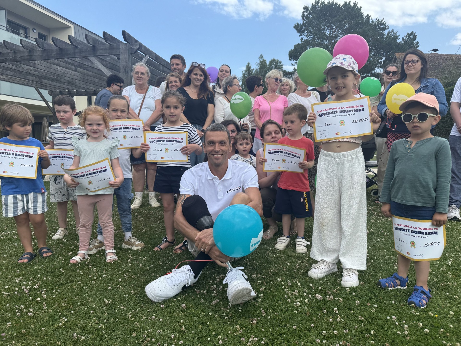 Alexis Hanquinquant entouré des enfants tenant leur diplôme Sécurité Aquatique, photo de groupe avec ballons